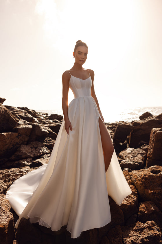 Abito da sposa Alya in raso opaco, con corpetto a corsetto e spalline sottili: un’eleganza essenziale vista di fronte.