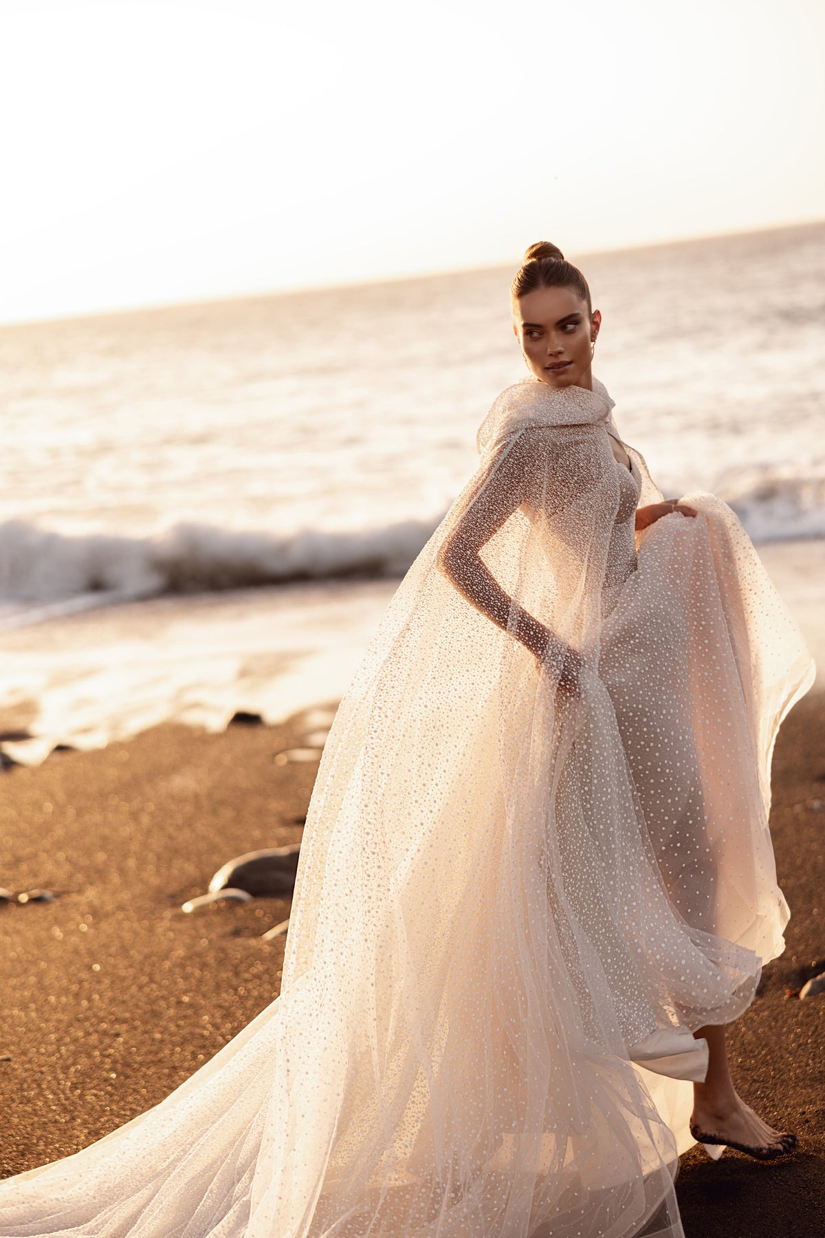 La leggera cappa in tulle con cappuccio Amira si può togliere dopo la cerimonia: un dettaglio romantico e scenografico.