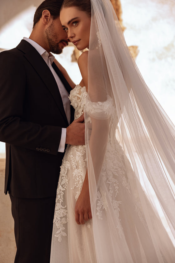 Il lungo velo da sposa Ariella in pizzo e morbido tulle crea un look romantico e sognante.