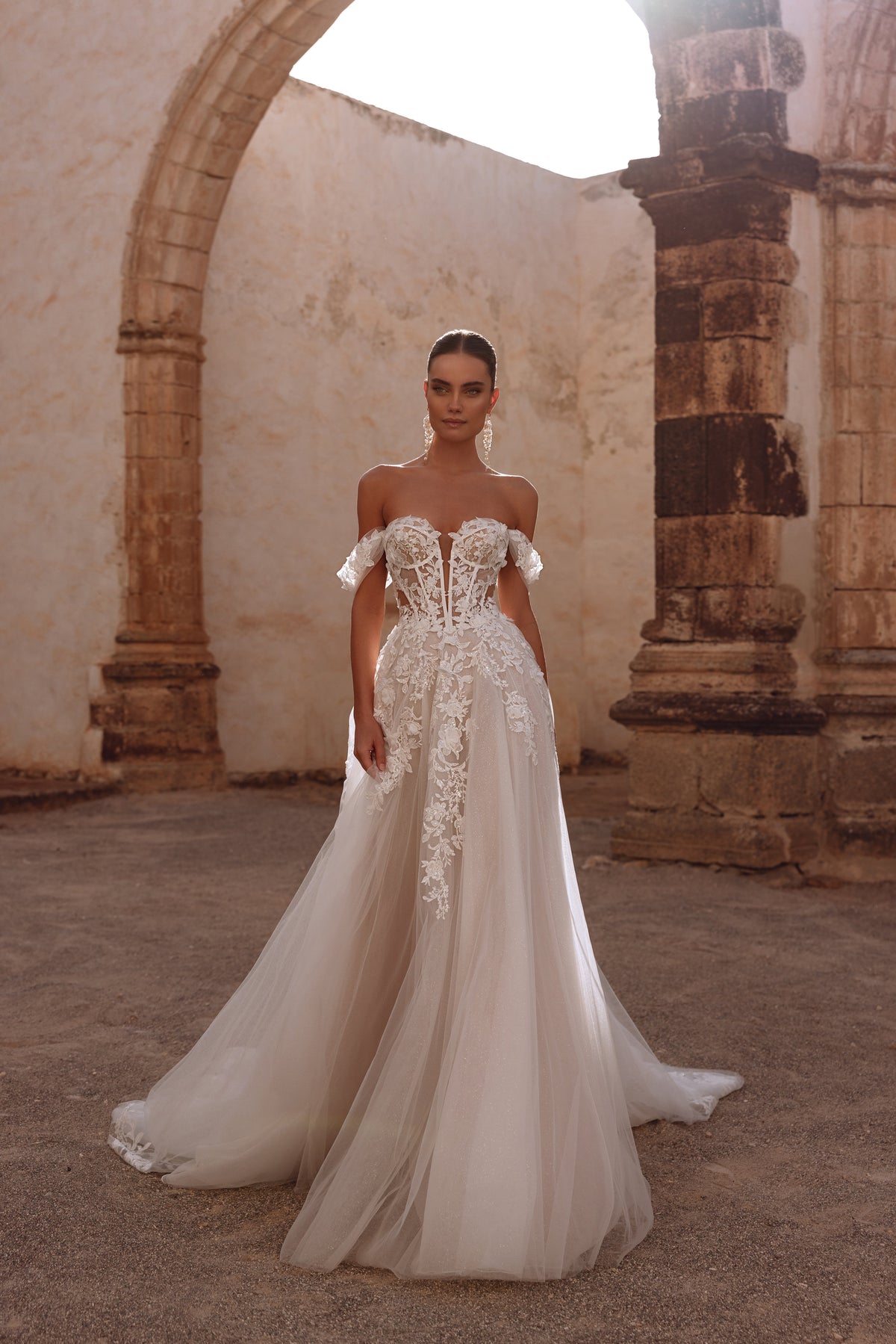 L’abito da sposa Ariella ha un corsetto con stecche a vista e intricate applicazioni di pizzo floreale, per un’eleganza delicata ed eterea.