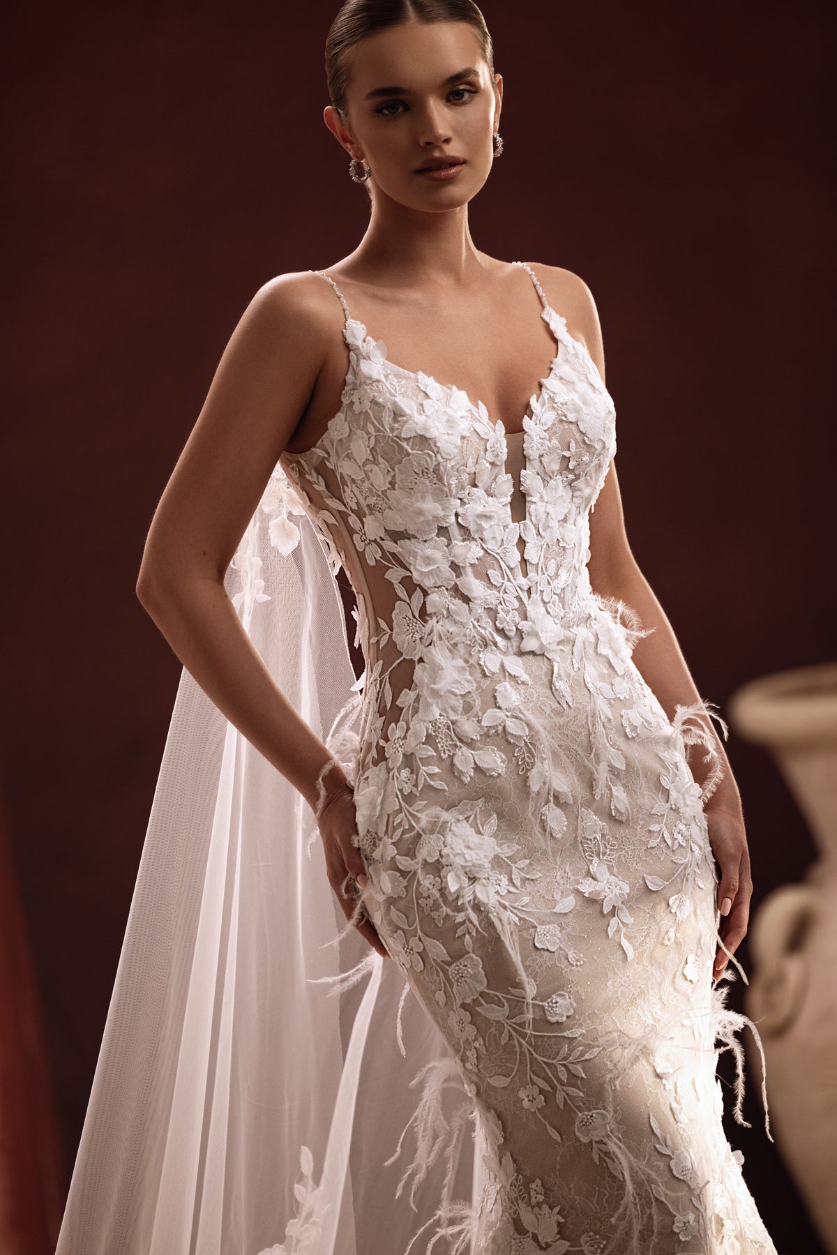 La lunga cappa da sposa Aspasia, con ricami in pizzo sullo strascico, crea un look prezioso ed elegante per il giorno del matrimonio.