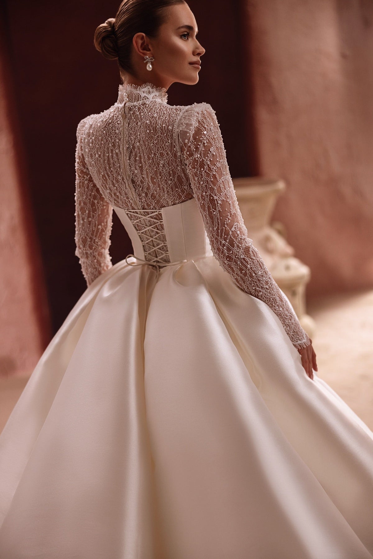 La sopragonna Henriette in raso, con scenografico strascico cattedrale, crea un look da sposa glamour e regale.