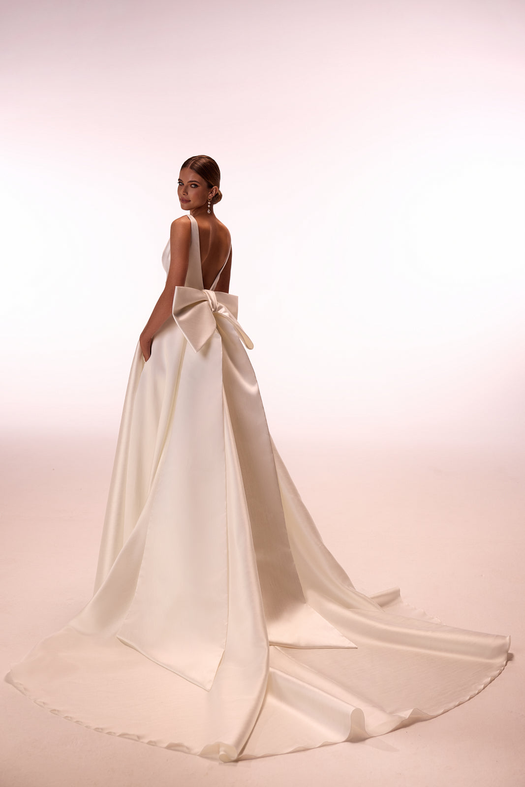 Abito da sposa classico Margo con strascico a fiocco di DAMA Couture (vista posteriore in studio)