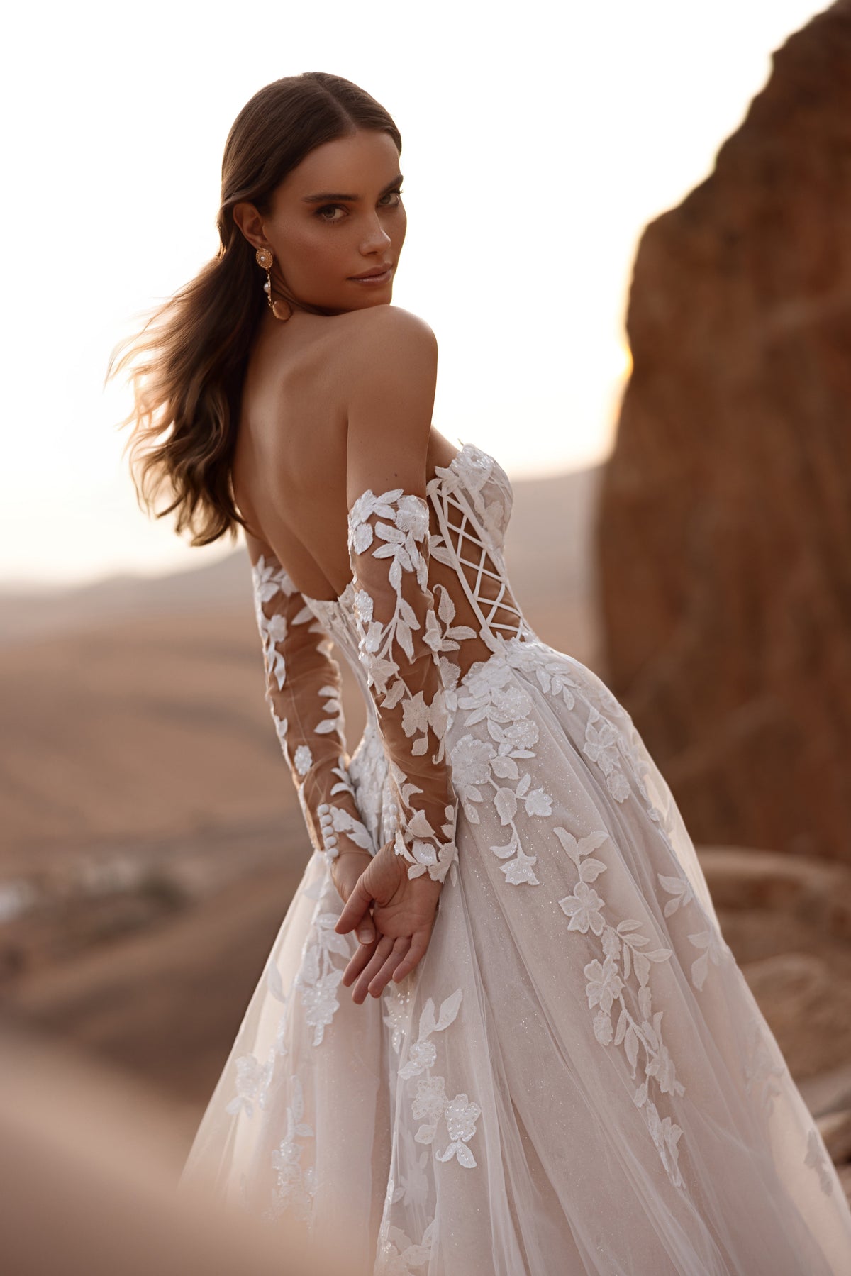 L’abito da sposa Nabila a principessa presenta uno scollo a spalle scoperte e uno strascico fluido in tulle, per un look d’effetto.