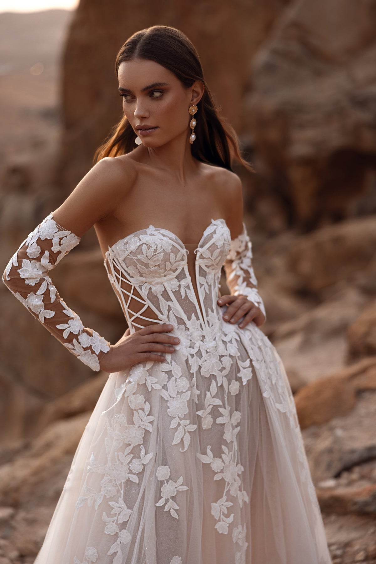 L’abito da sposa Nabila, con lungo velo e dettagli in pizzo floreale, propone un’eleganza sognante e senza tempo.