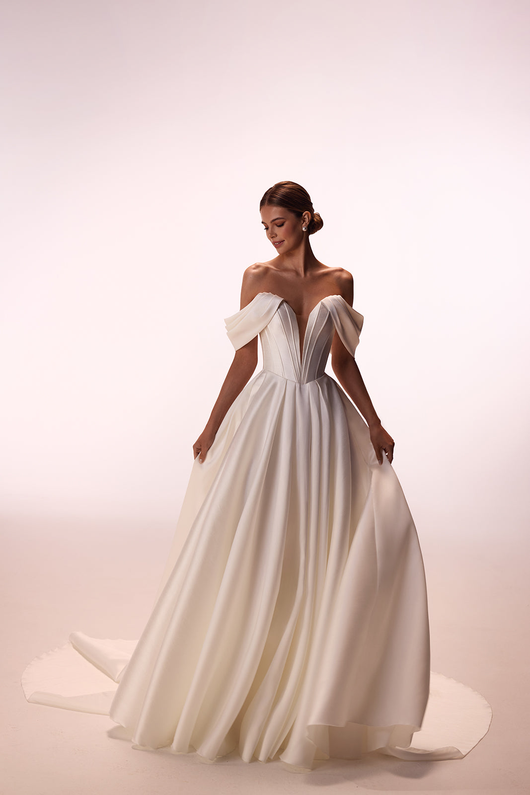 Abito da sposa Thalia classico ed essenziale, con maniche che scendono dalle spalle, di DAMA Couture (foto in studio)