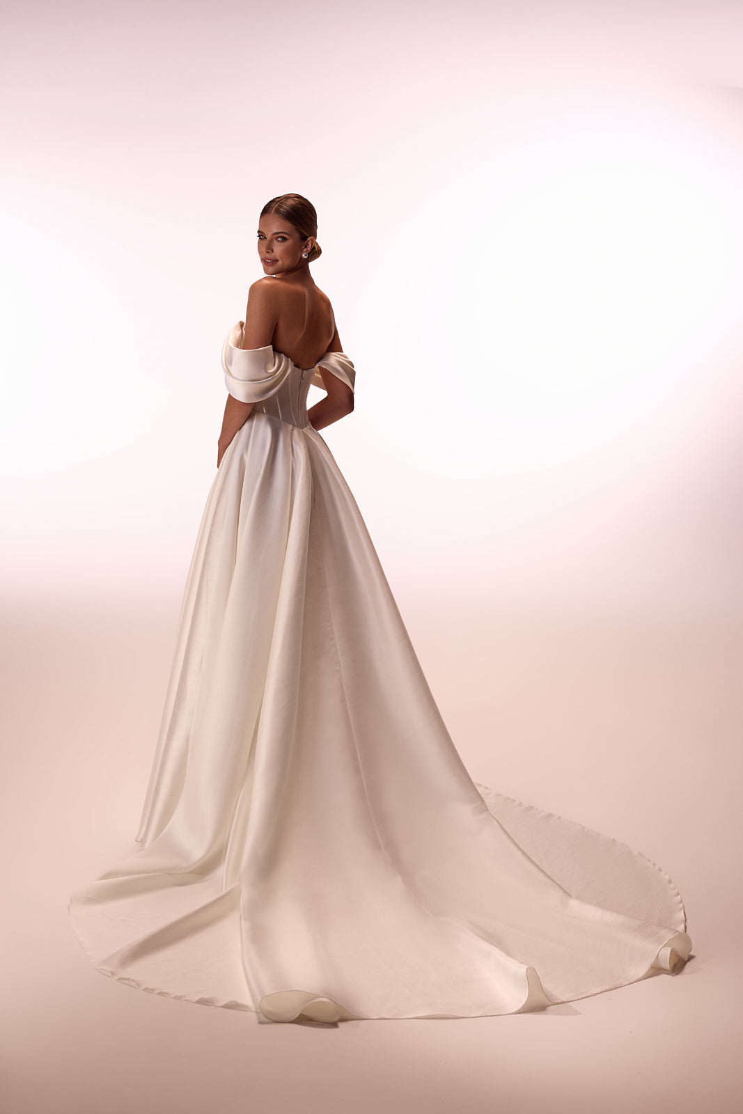 Abito da sposa Thalia classico ed essenziale, con maniche che scendono dalle spalle, di DAMA Couture (vista posteriore in studio)