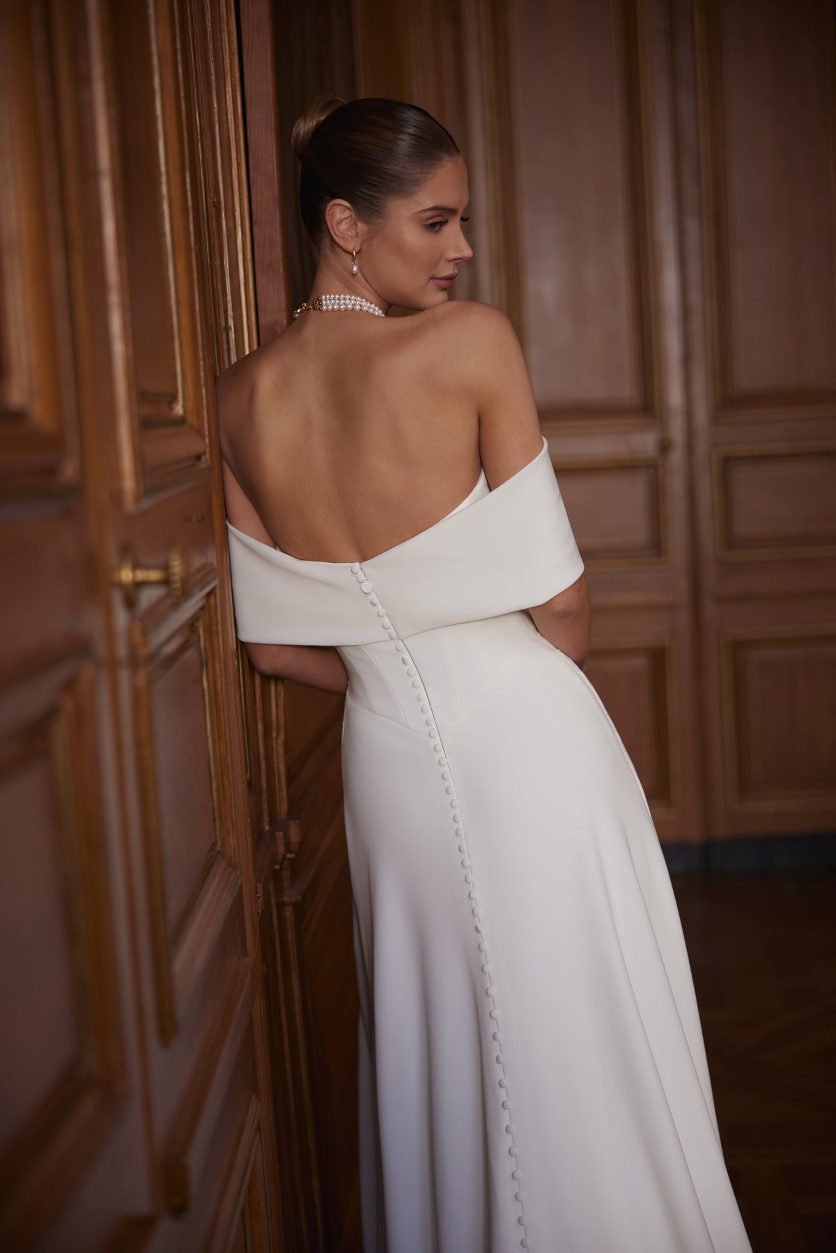Abito da sposa Calliope – un ampio scollo che lascia le spalle scoperte e una gonna in raso dalle linee essenziali con spacco.