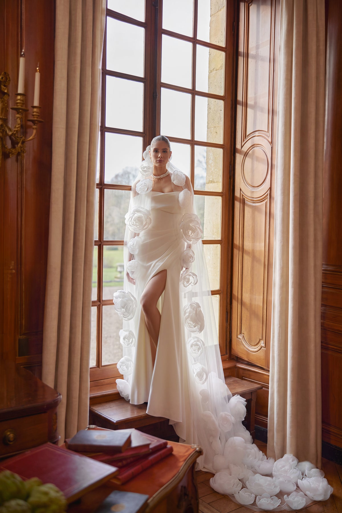 Velo Calliope: lungo velo in tulle bordato di pizzo, indossato con l’abito da sposa Calliope.