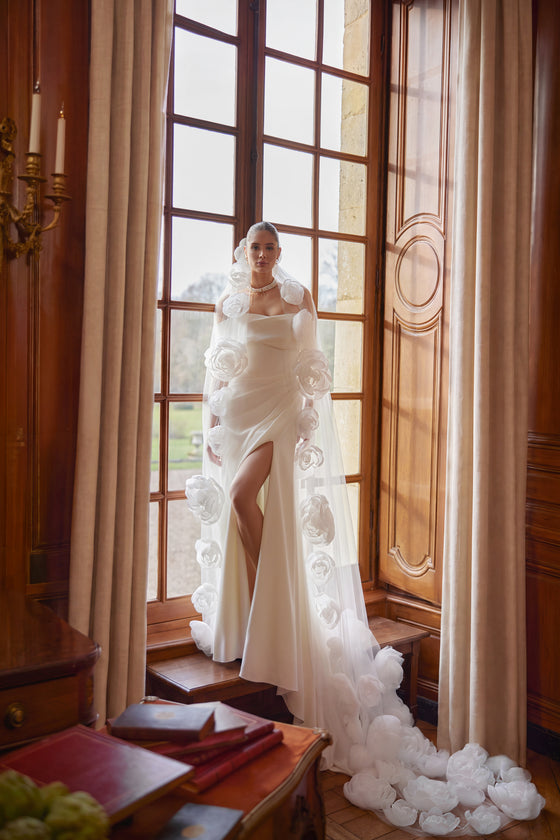 Velo Calliope: lungo velo in tulle bordato di pizzo, indossato con l’abito da sposa Calliope.