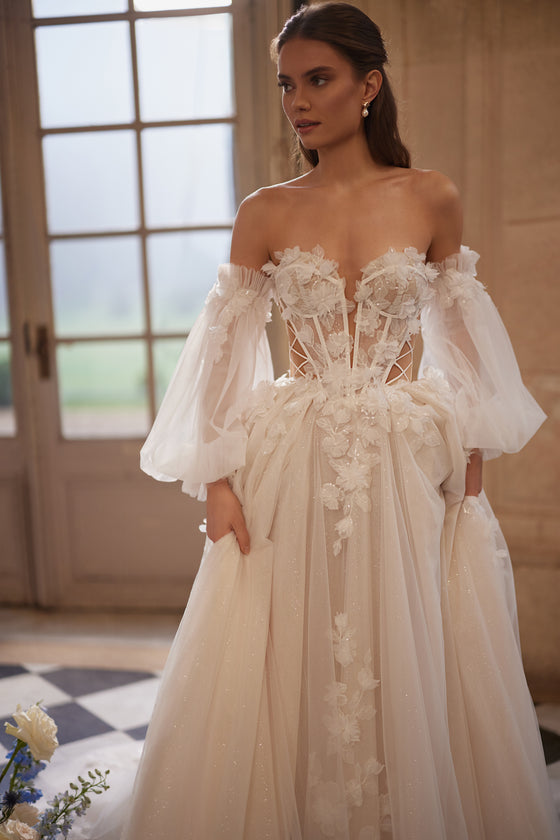 Abito da sposa Celestine – abito da sposa a trapezio con uno scollo aperto, leggere maniche che lasciano le spalle scoperte e fiori in 3D.