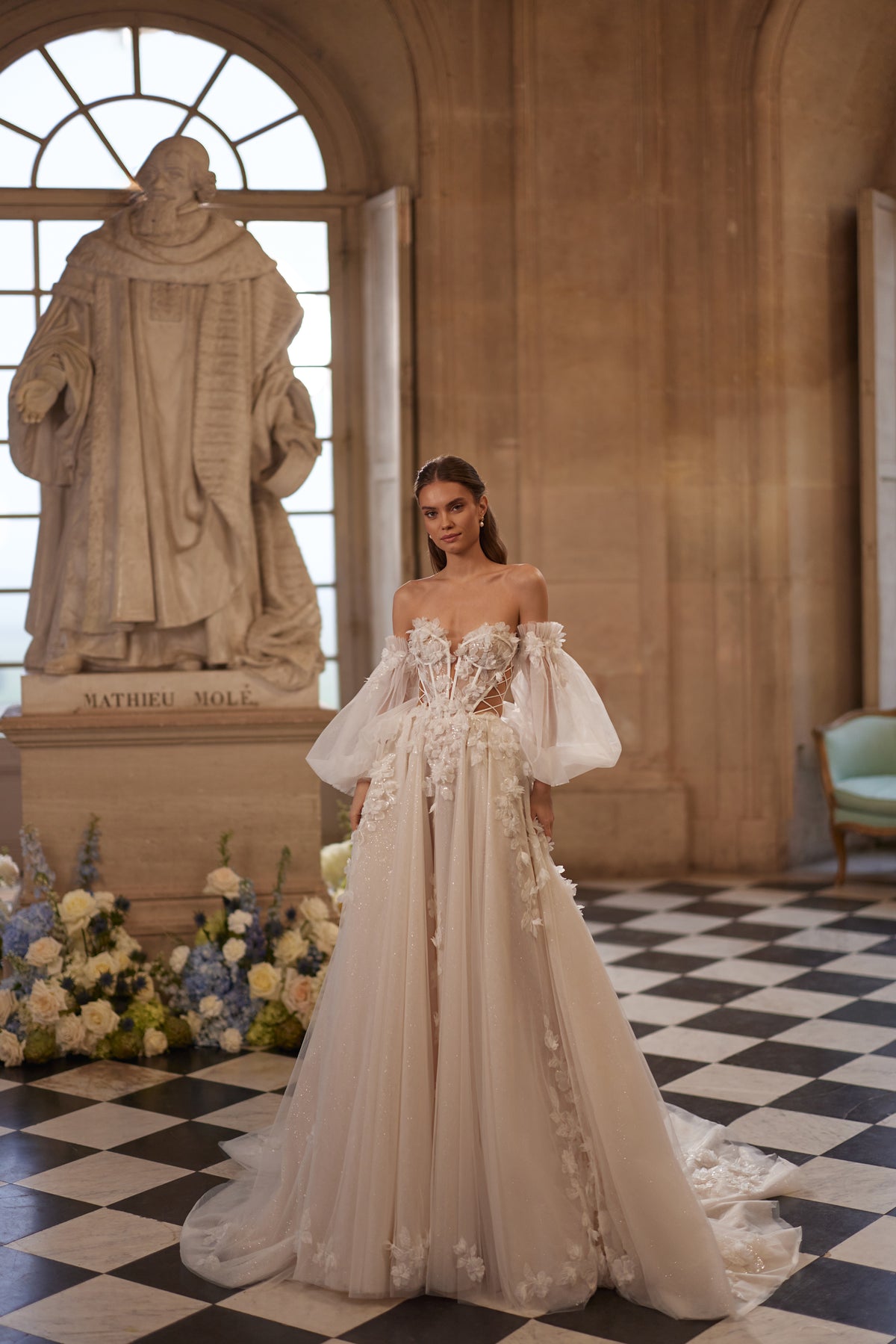 Abito da sposa Celestine – uno scollo aperto, leggere maniche che lasciano le spalle scoperte e fiori in 3D, DAMA Couture Something Blue 2027.