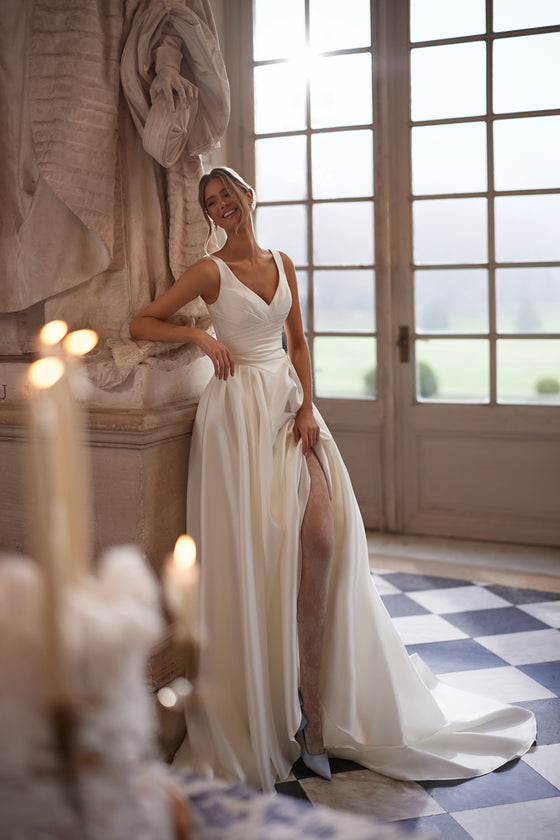 Abito da sposa Elvira – abito da sposa a trapezio con uno scollo a V aperto e una gonna drappeggiata dalle linee essenziali con spacco alto.
