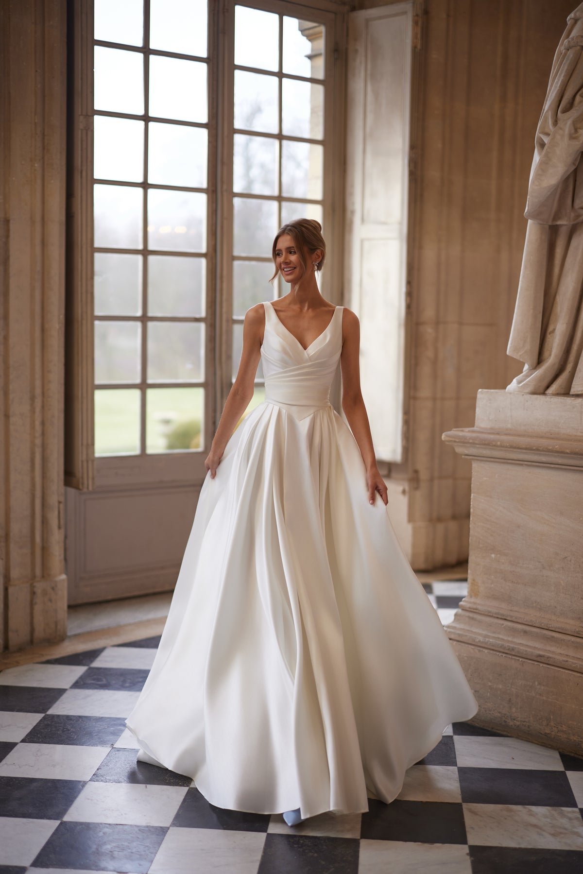Abito da sposa Elvira – uno scollo a V aperto e una gonna drappeggiata dalle linee essenziali con spacco alto.