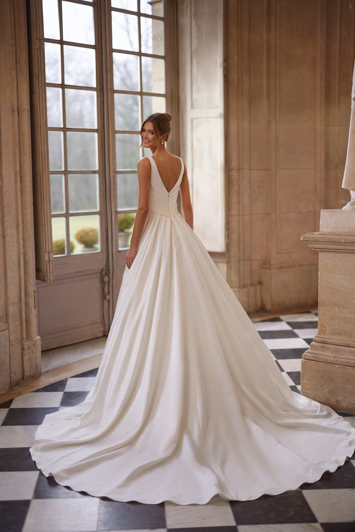 Abito da sposa Elvira della collezione Something Blue 2027 – uno scollo a V aperto e una gonna drappeggiata dalle linee essenziali con spacco alto.