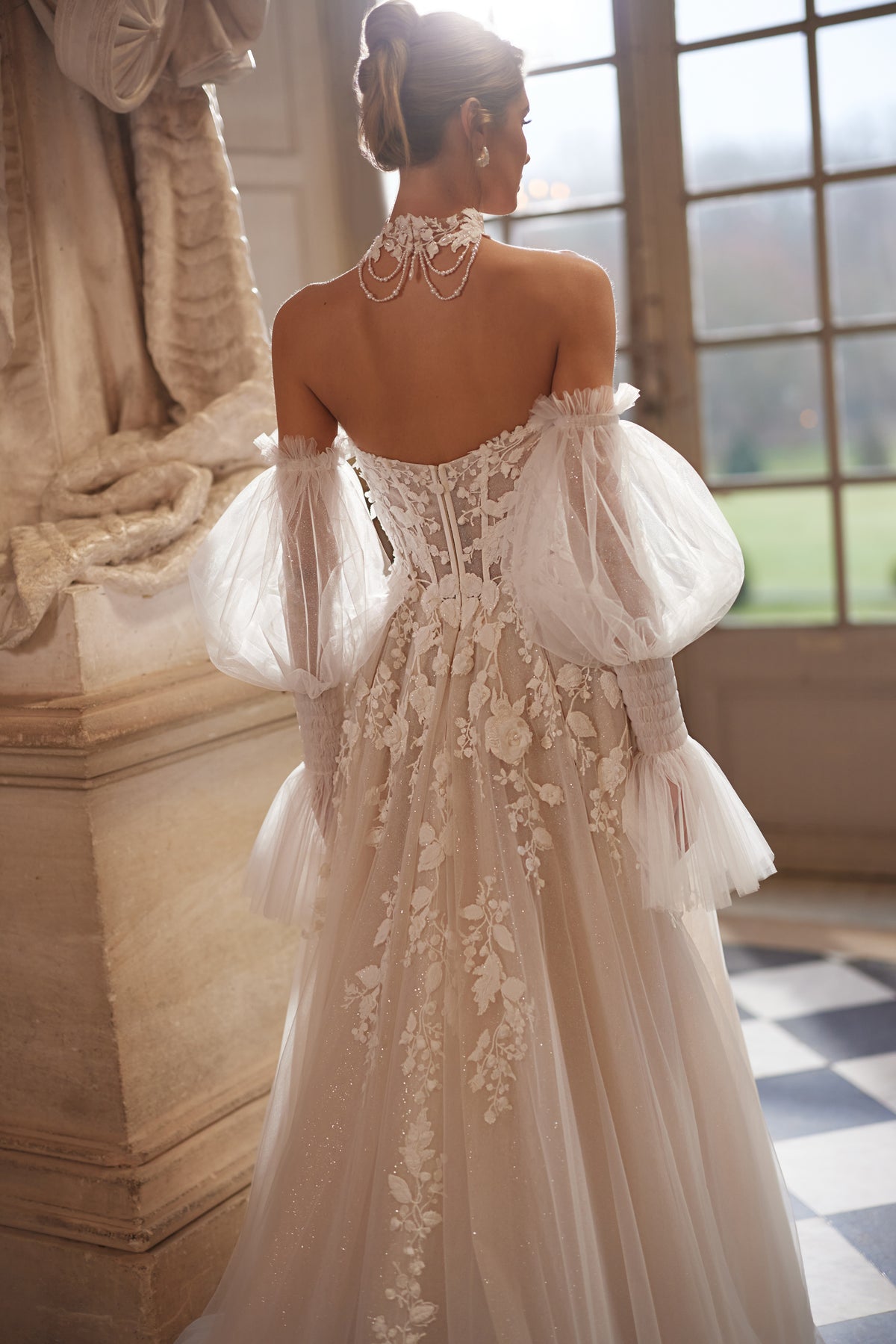 Abito da sposa Estella – un corsetto con fiori in rilievo e voluminose maniche che lasciano le spalle scoperte.