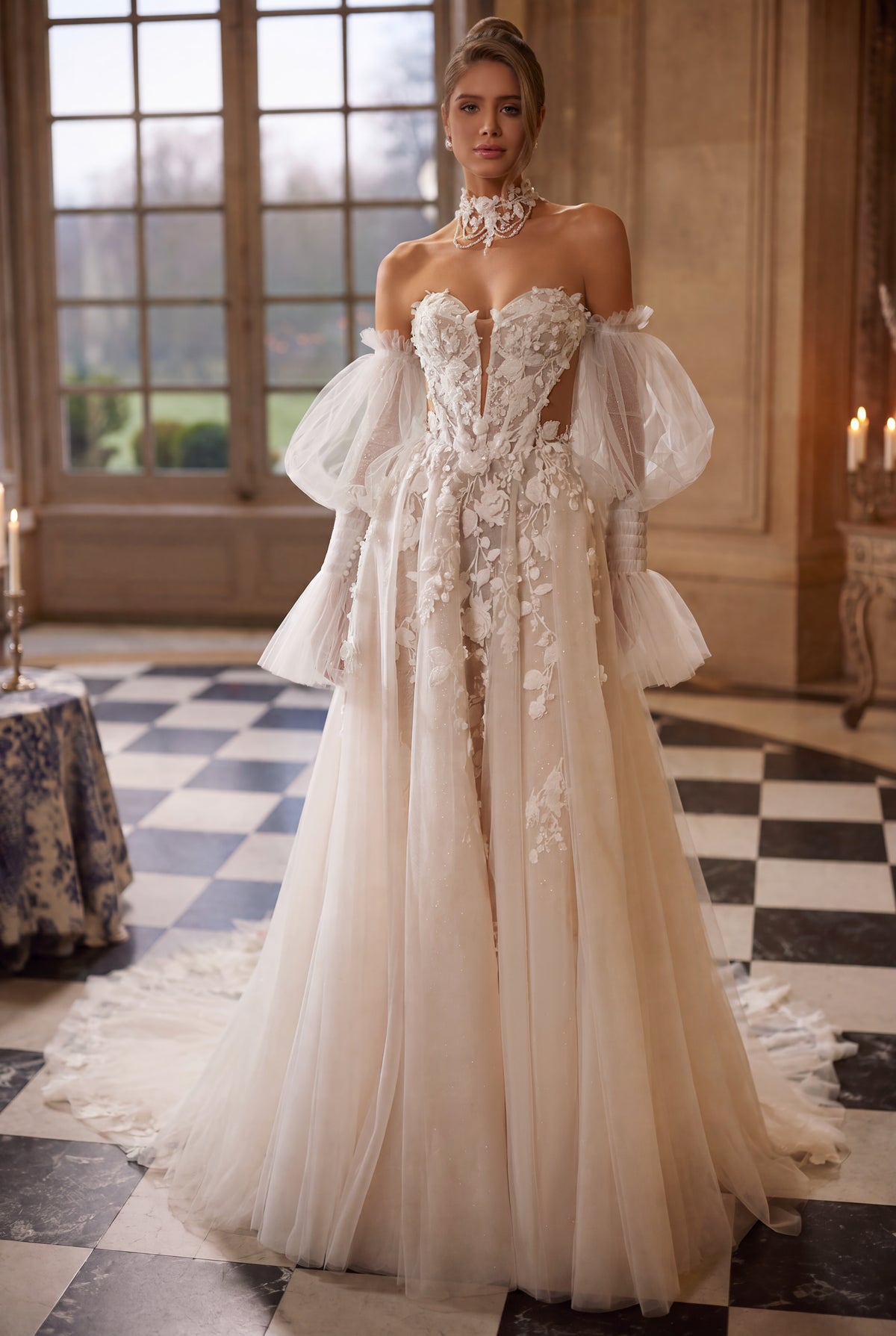 Abito da sposa Estella – silhouette a trapezio con un corsetto con fiori in rilievo e voluminose maniche che lasciano le spalle scoperte.