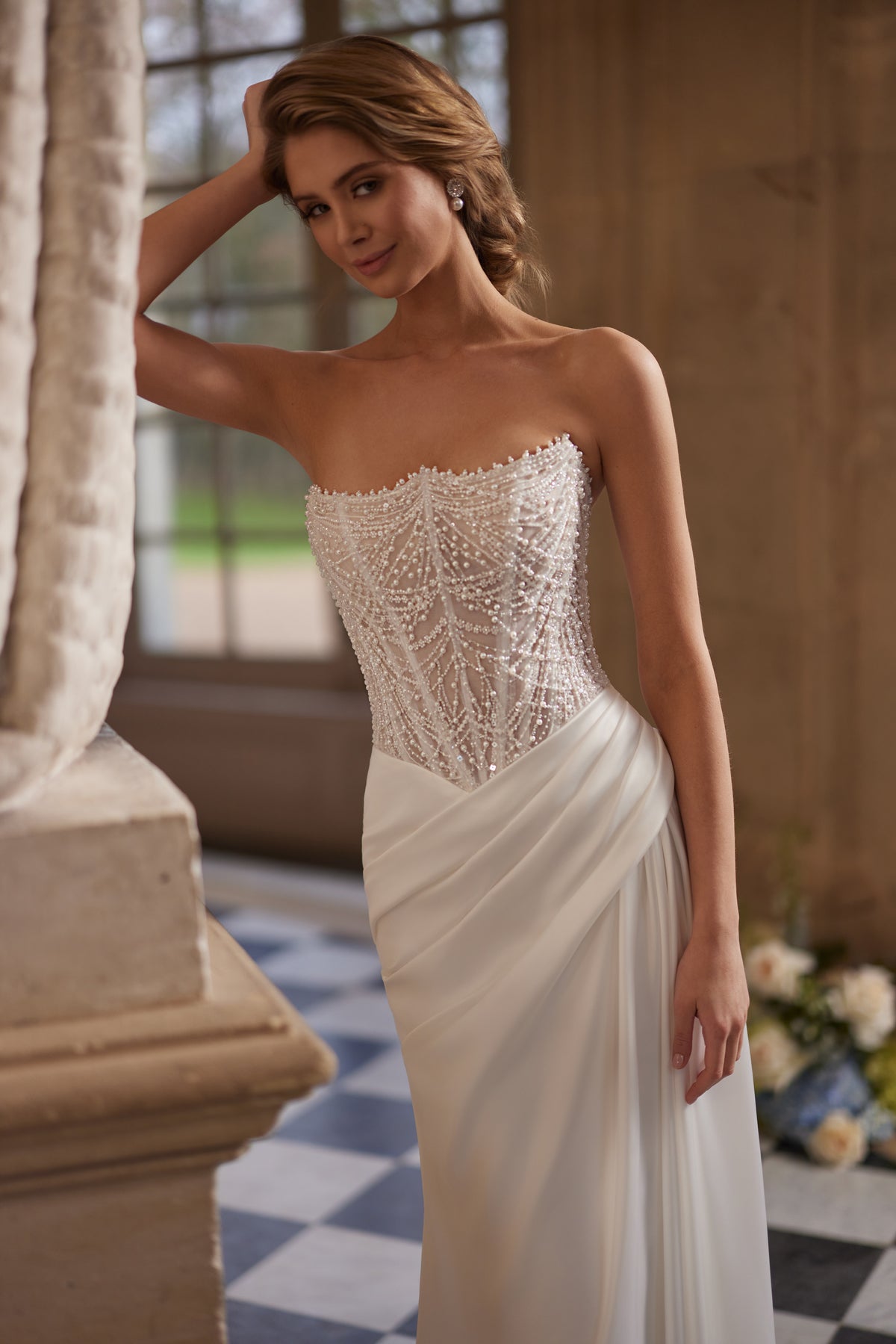 Abito da sposa Greta – un corsetto senza spalline riccamente decorato di perline e una gonna drappeggiata in raso.