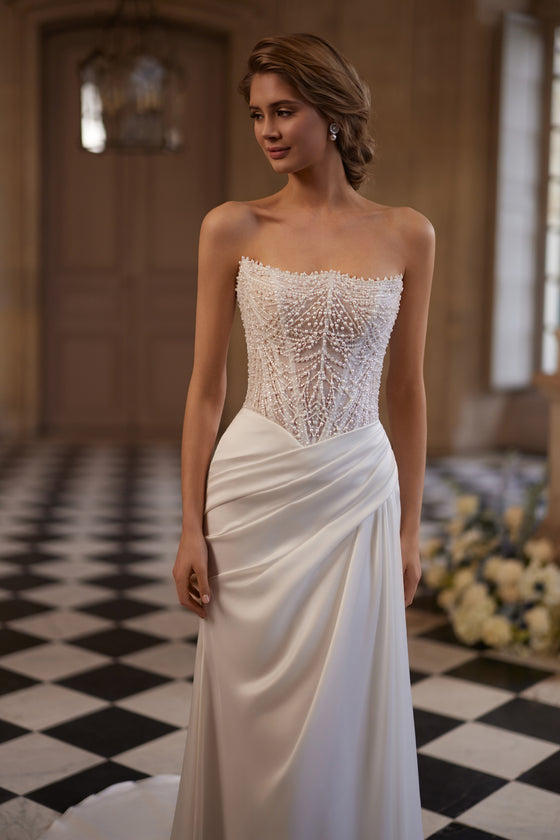 Abito da sposa Greta – un corsetto senza spalline riccamente decorato di perline e una gonna drappeggiata in raso, DAMA Couture Something Blue 2027.