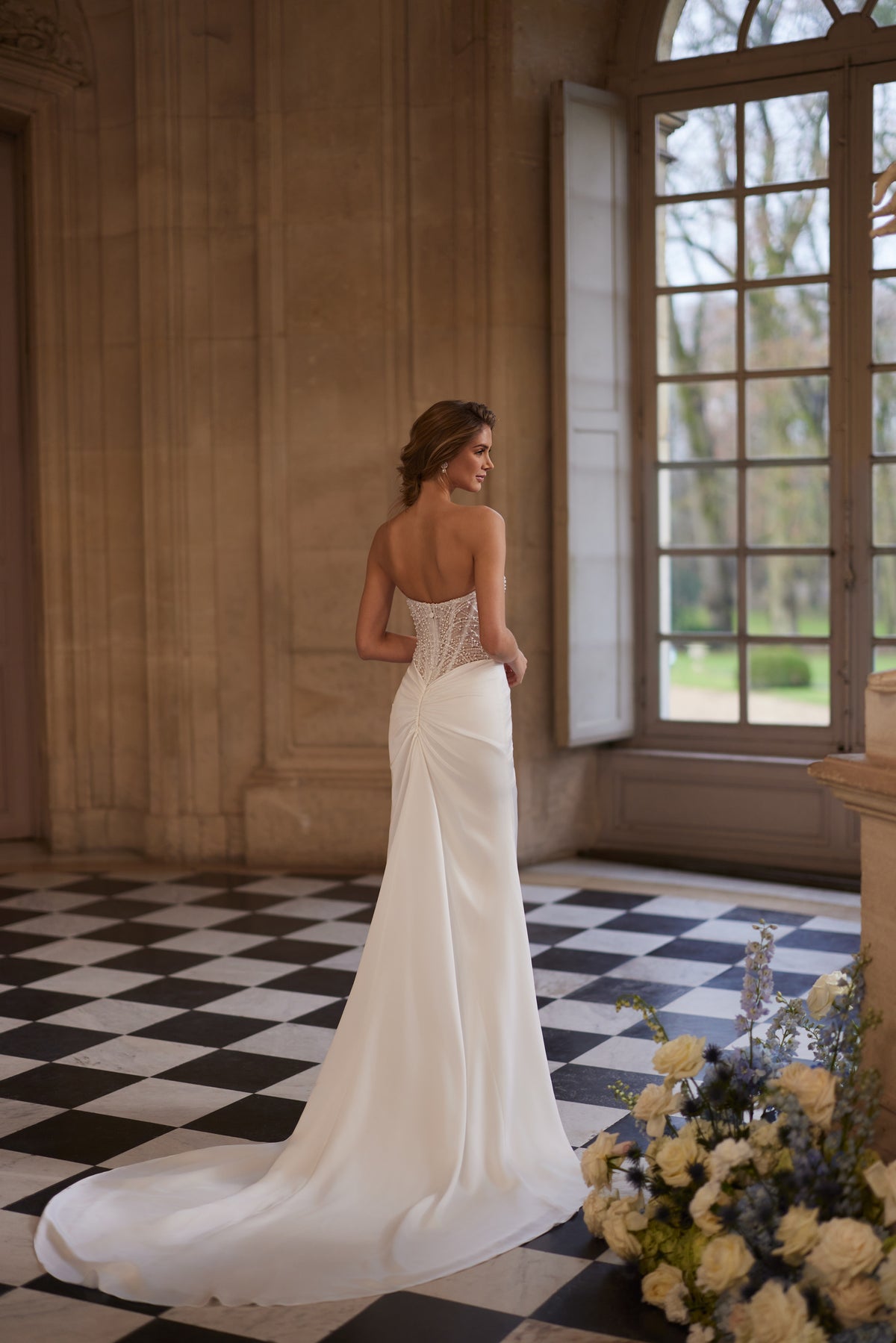 Abito da sposa Greta della collezione Something Blue 2027 – un corsetto senza spalline riccamente decorato di perline e una gonna drappeggiata in raso.