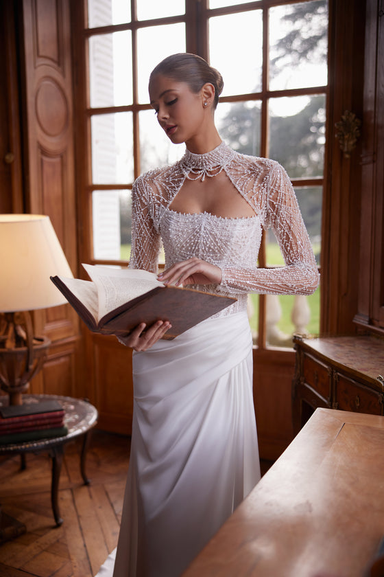 Abito da sposa Greta – silhouette a sirena con un corsetto senza spalline riccamente decorato di perline e una gonna drappeggiata in raso.