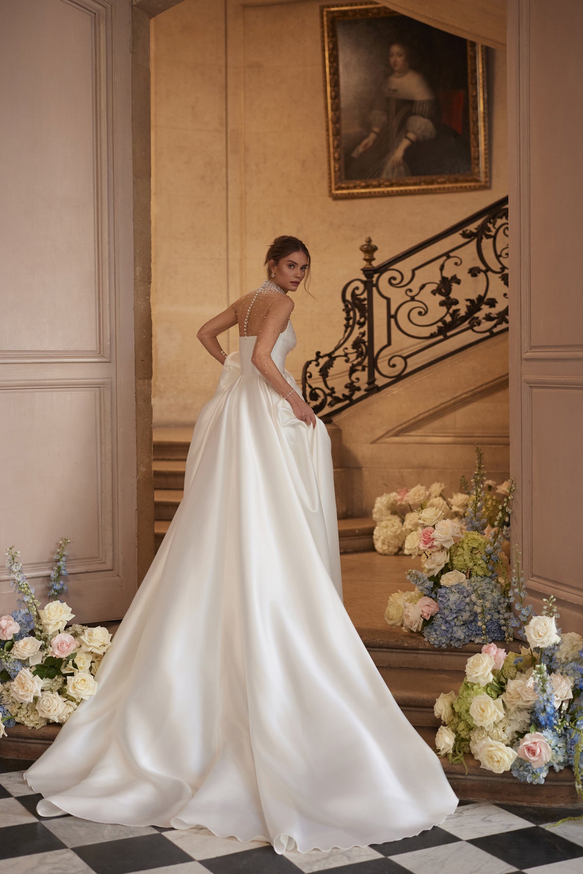 Abito da sposa Lucienne della collezione Something Blue 2027 – uno scollo effetto illusion decorato di cristalli e una gonna drappeggiata in raso con spacco alto.