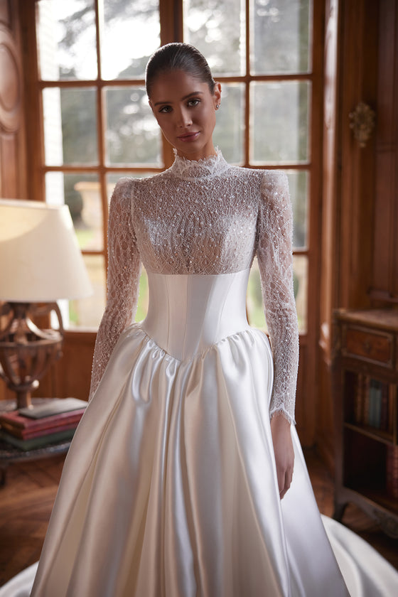 Abito da sposa Maristella – abito da sposa a trapezio con un corpetto in pizzo a collo alto con maniche lunghe e un’ampia gonna in raso.