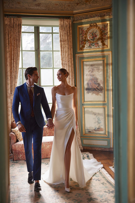 Abito da sposa Sodden – abito da sposa a sirena con uno scollo senza spalline morbidamente drappeggiato e uno spacco alto, in raso fluido.