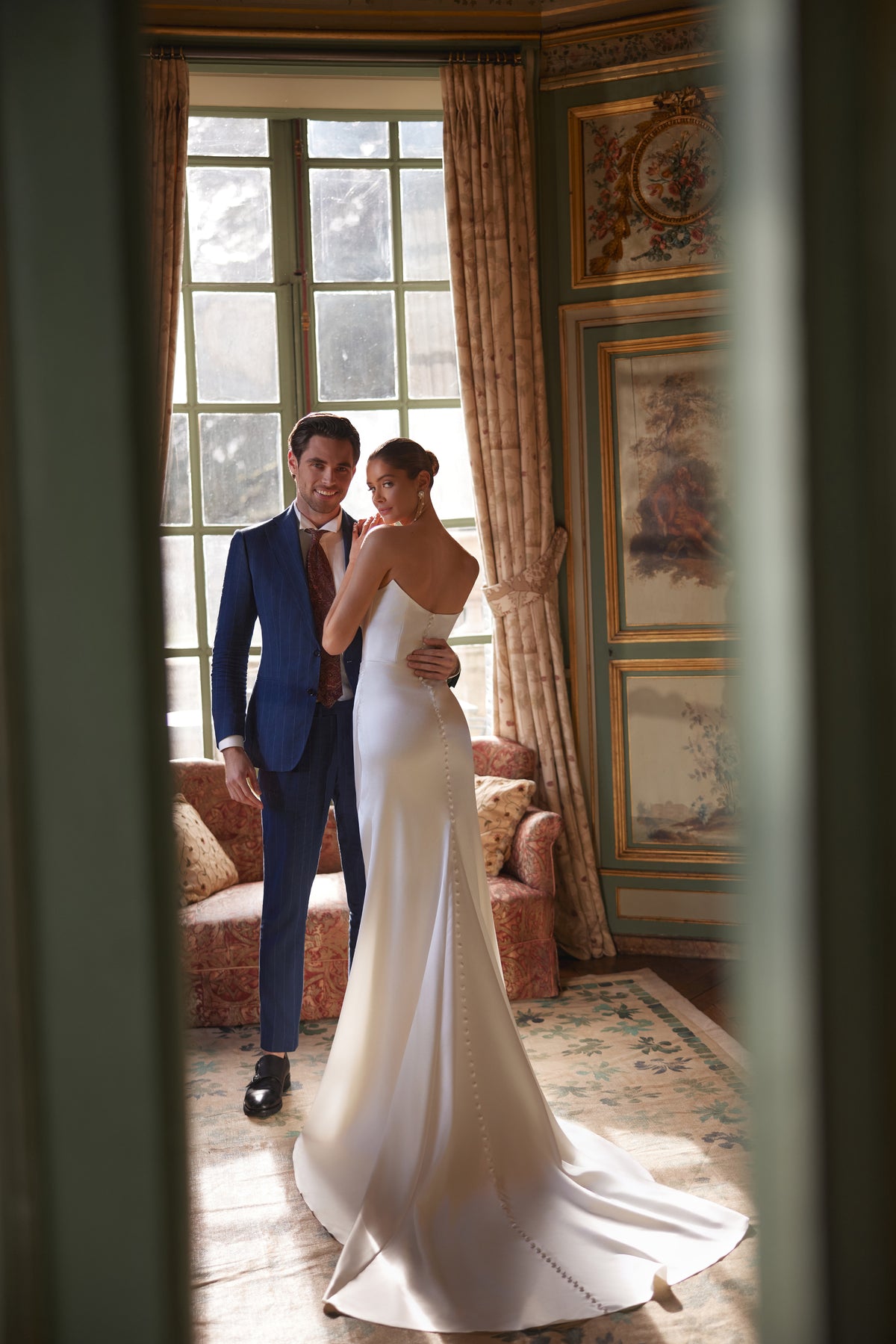 Abito da sposa Sodden – silhouette a sirena con uno scollo senza spalline morbidamente drappeggiato e uno spacco alto, in raso fluido.