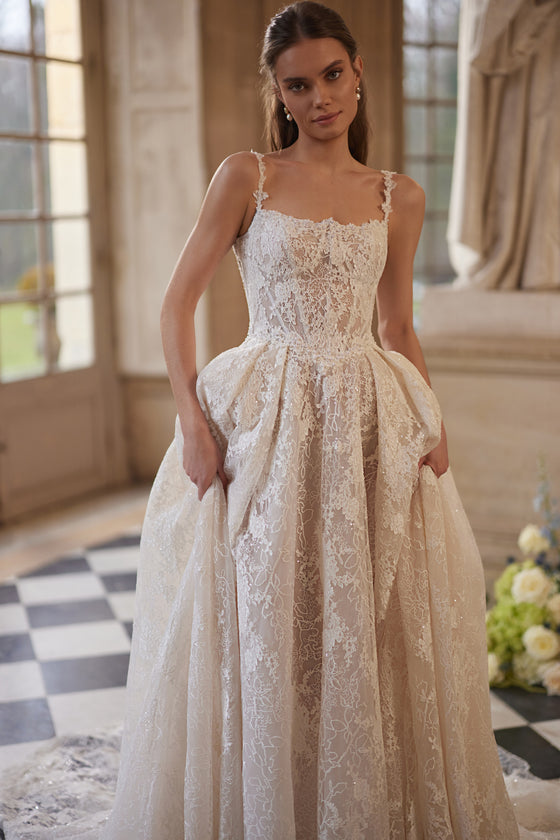 Abito da sposa Thetis – abito da sposa a trapezio con un corsetto trasparente, spalline in pizzo e una ricca gonna in pizzo.