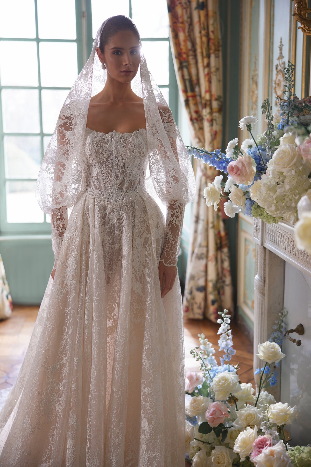 Abito da sposa Thetis – silhouette a trapezio con un corsetto trasparente, spalline in pizzo e una ricca gonna in pizzo.