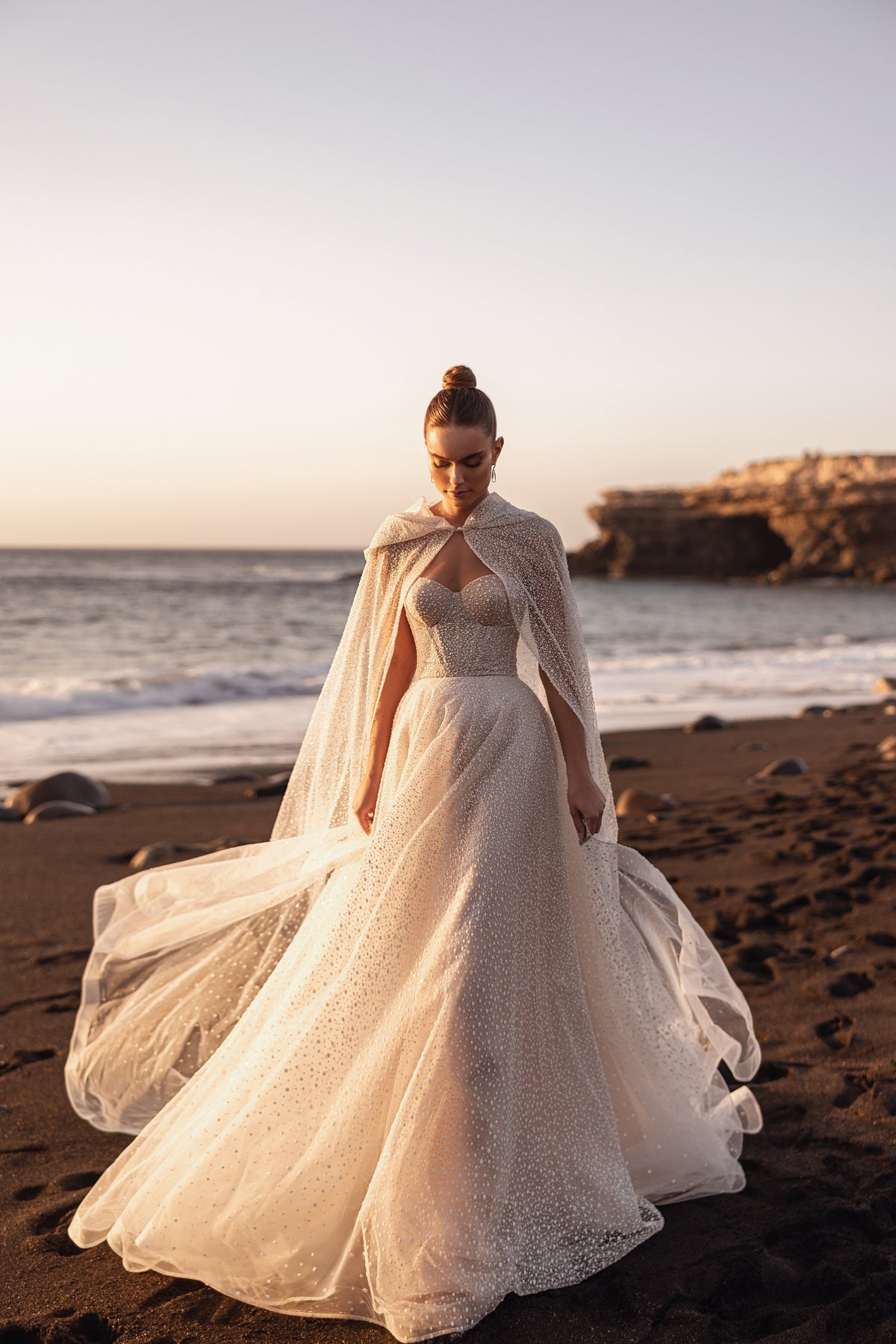 Cappa da sposa Amira abbinata a un abito con corsetto senza spalline, per un look da fiaba.