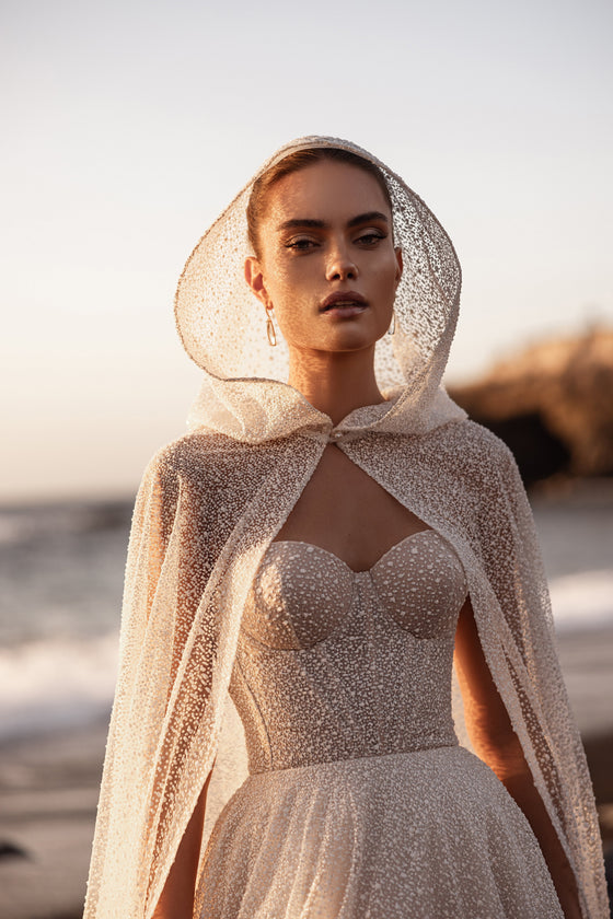 Cappa da sposa Amira con delicato cappuccio e tulle decorato d’ispirazione couture.