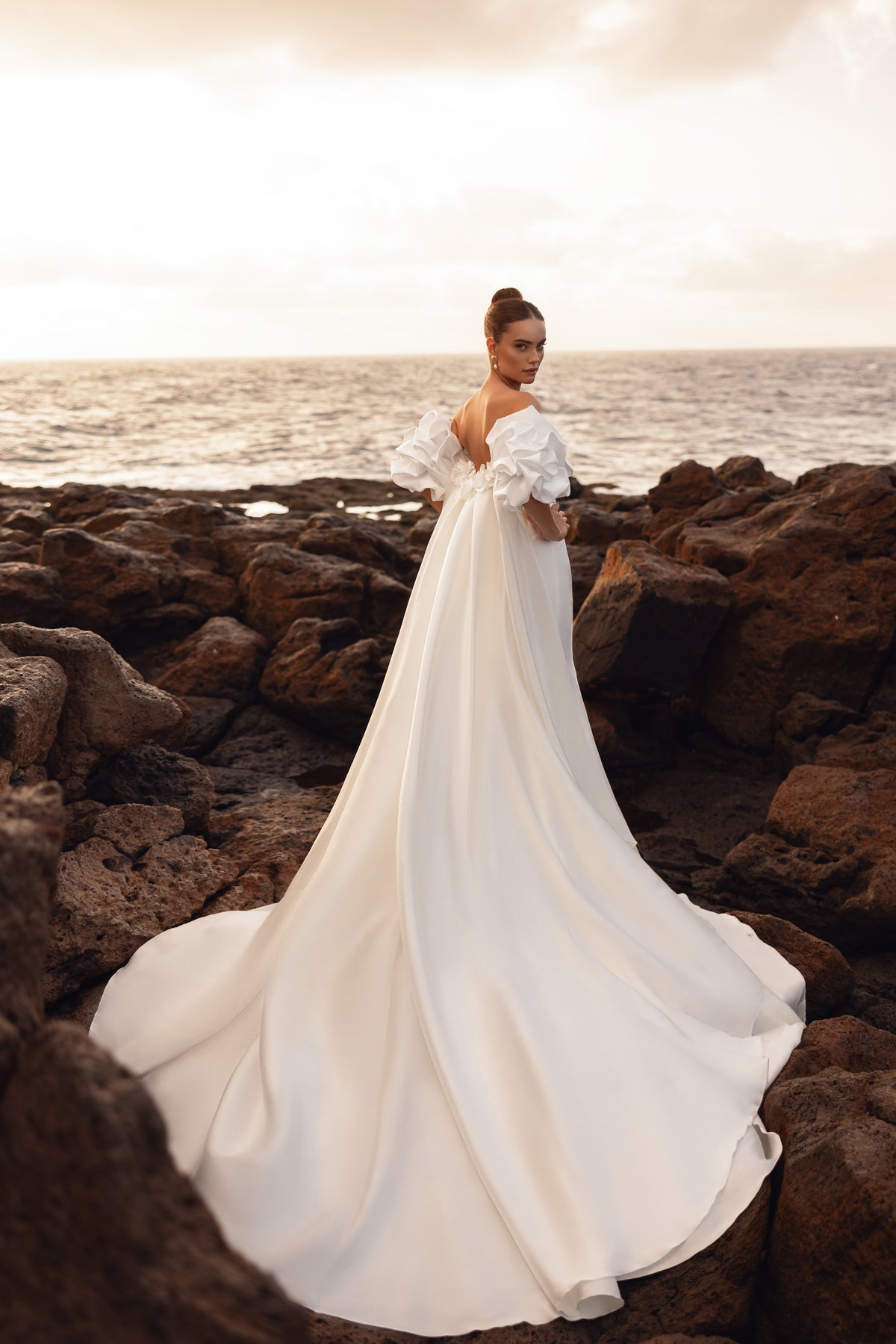 Abito da sposa con schiena scoperta e strascico extra lungo, per ritratti scenografici in riva al mare.