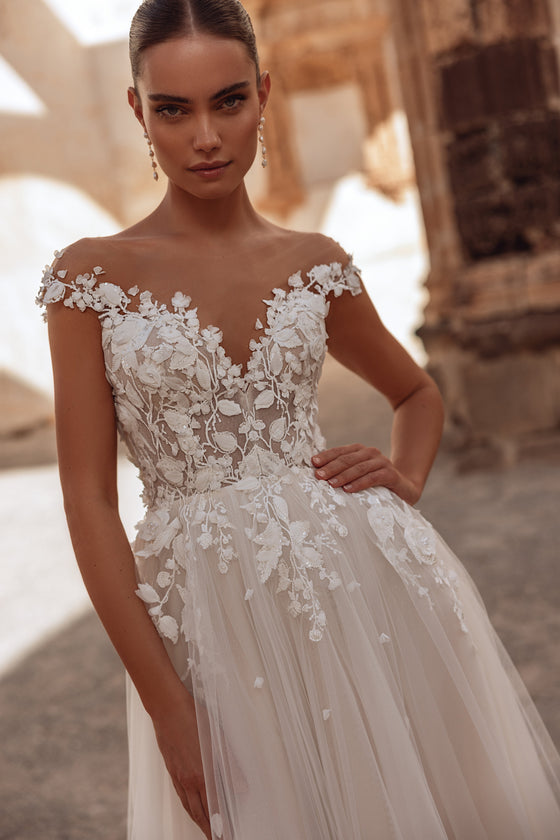 L’abito da sposa Andrea presenta un corpetto in pizzo floreale 3D e una gonna fluida in tulle, per un look romantico e sognante.
