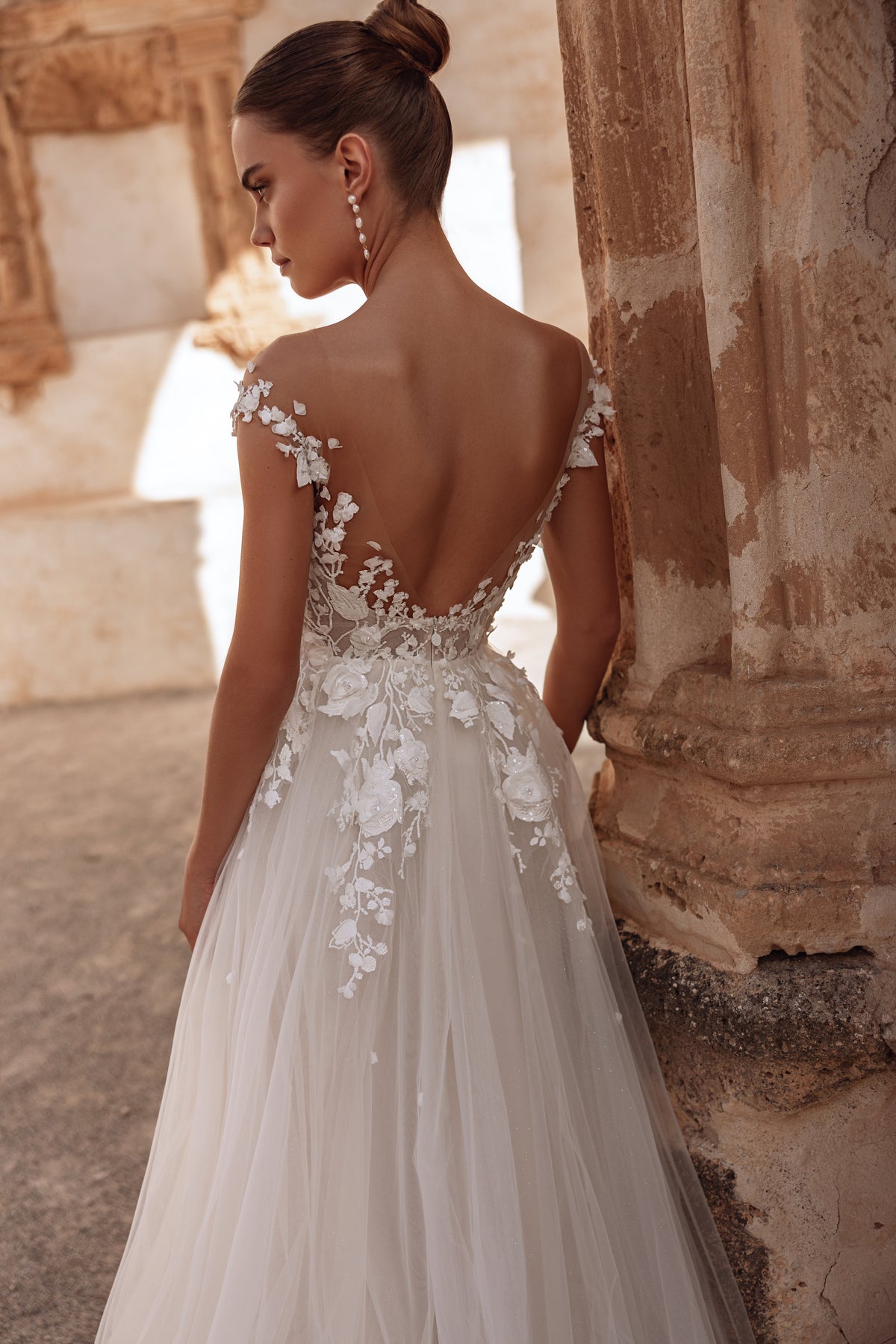 L’abito da sposa Andrea, con schiena scoperta e lungo strascico fluido, unisce eleganza eterea e romanticismo contemporaneo.