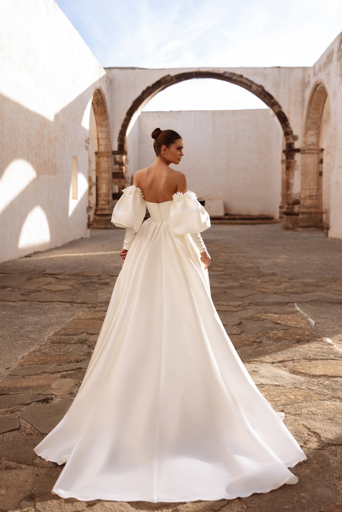 Abito da sposa lungo Anika, con maniche che lasciano scoperte le spalle e uno strascico elegante, per un look regale.