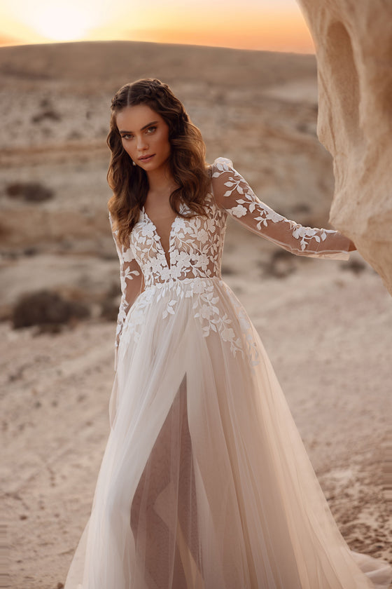L’abito da sposa Armori, con lungo strascico in tulle e corpetto in pizzo, risplende sullo sfondo del tramonto nel deserto.
