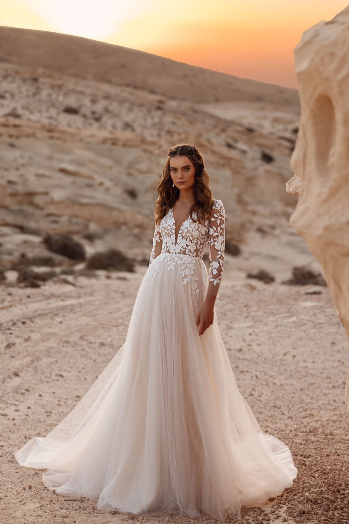 L’abito da sposa Armori presenta un profondo scollo a V e maniche in pizzo a tre quarti, per un look romantico e senza tempo.