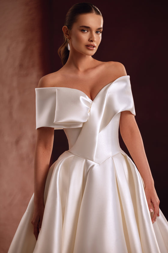 Il dettaglio dell’abito da sposa Avin mostra la luminosità preziosa del raso e lo scollo scultoreo che lascia scoperte le spalle.