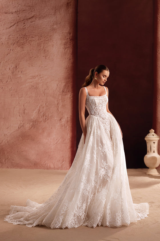 L’abito da sposa Becco presenta un corpetto a corsetto in pizzo con allacciatura sulla schiena, unendo eleganza classica e carattere romantico.