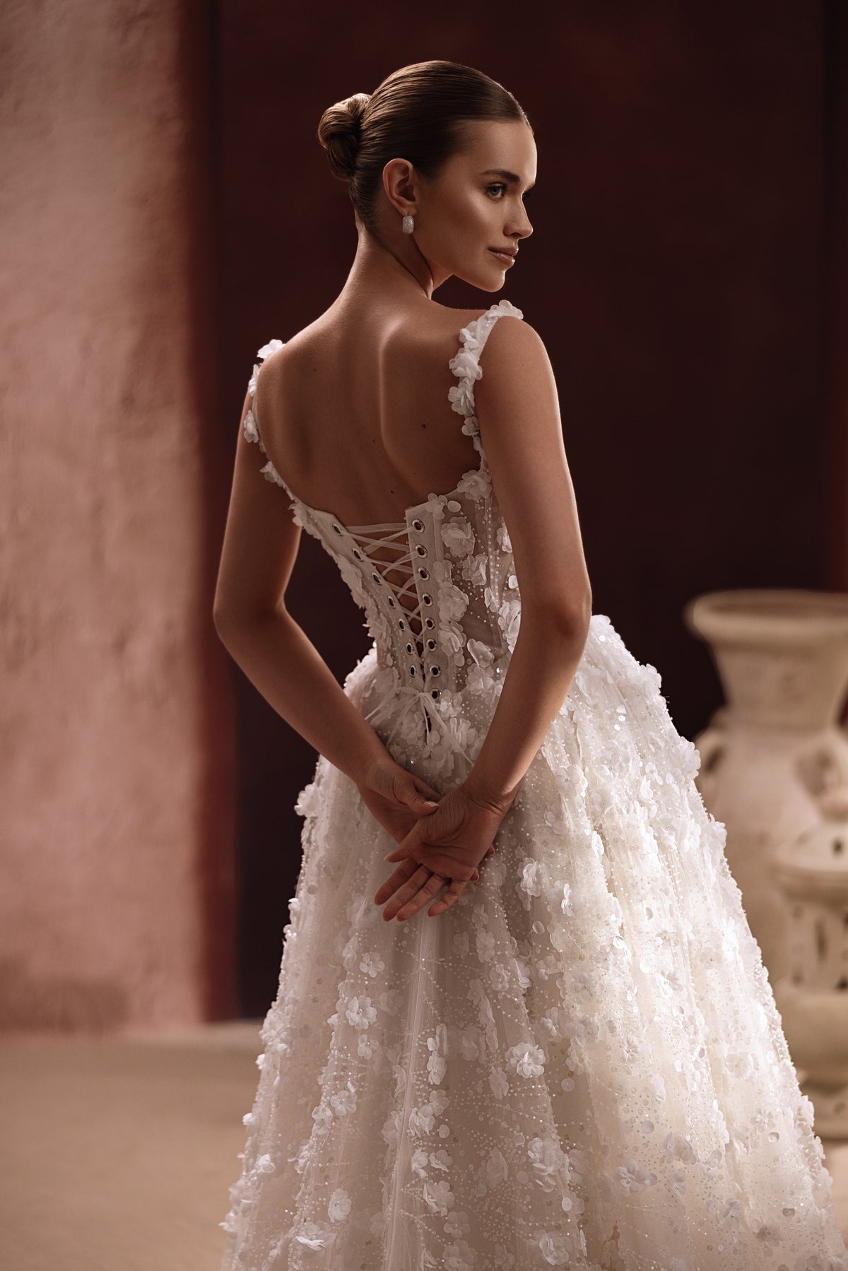 L’abito da sposa Cintra mostra un corpetto in pizzo trasparente decorato con applicazioni floreali, per uno stile raffinato e romantico.