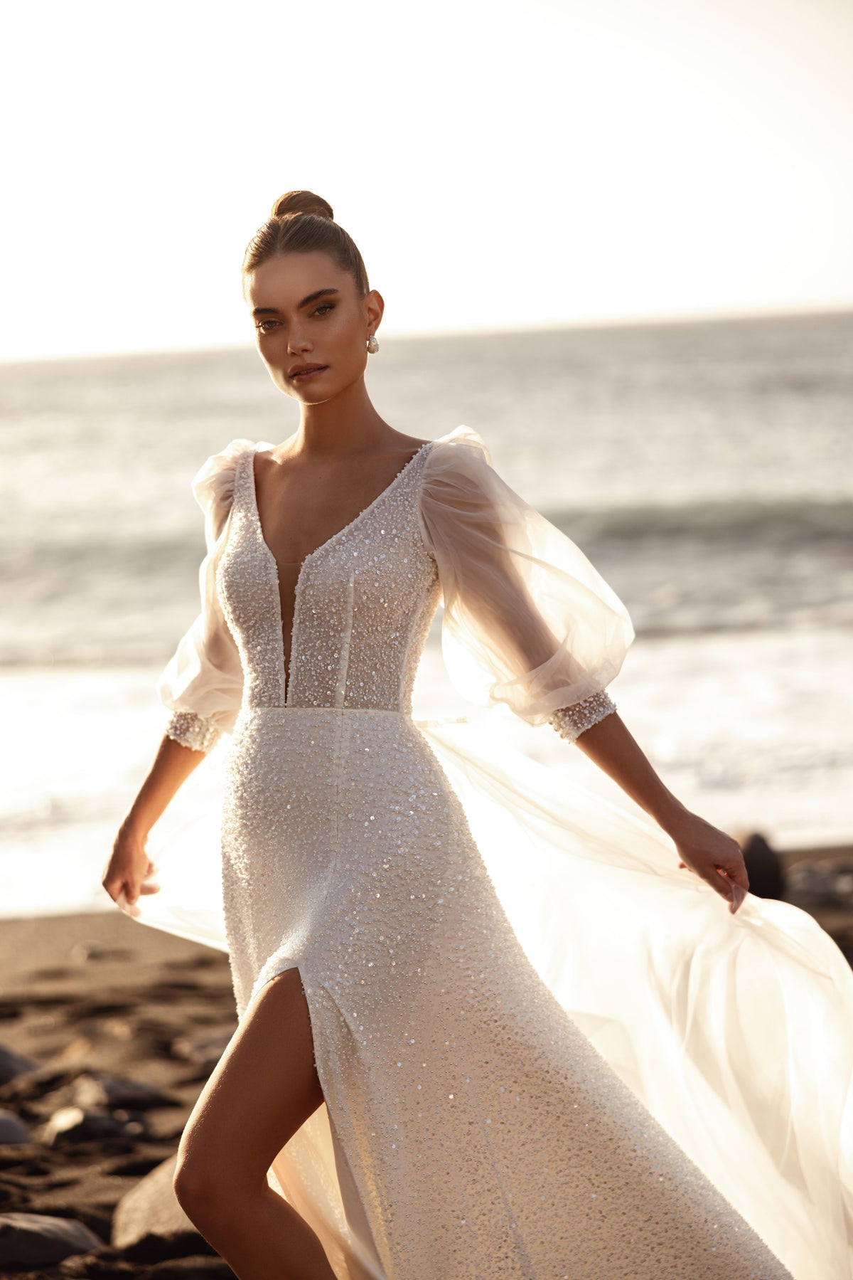 L’abito da sposa Davina, con maniche a sbuffo trasparenti e dettagli scintillanti, esprime eleganza e leggerezza nella luce del sole.