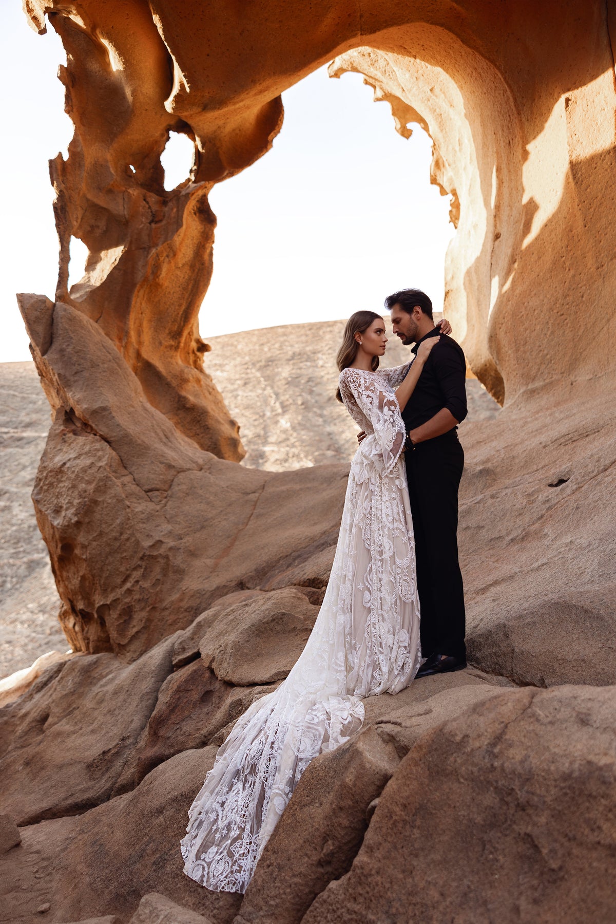 L’abito da sposa Dune presenta un corpetto in pizzo trasparente e maniche a campana con intricati ricami floreali, per un look boho romantico.