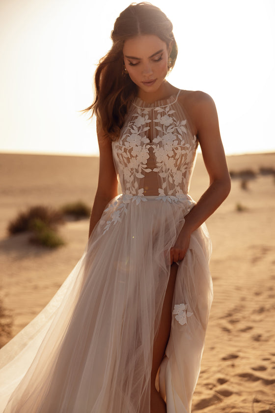 L’abito da sposa Ellie, con scollo all’americana e leggeri strati di tulle, evoca un matrimonio all’aperto dall’atmosfera sognante.