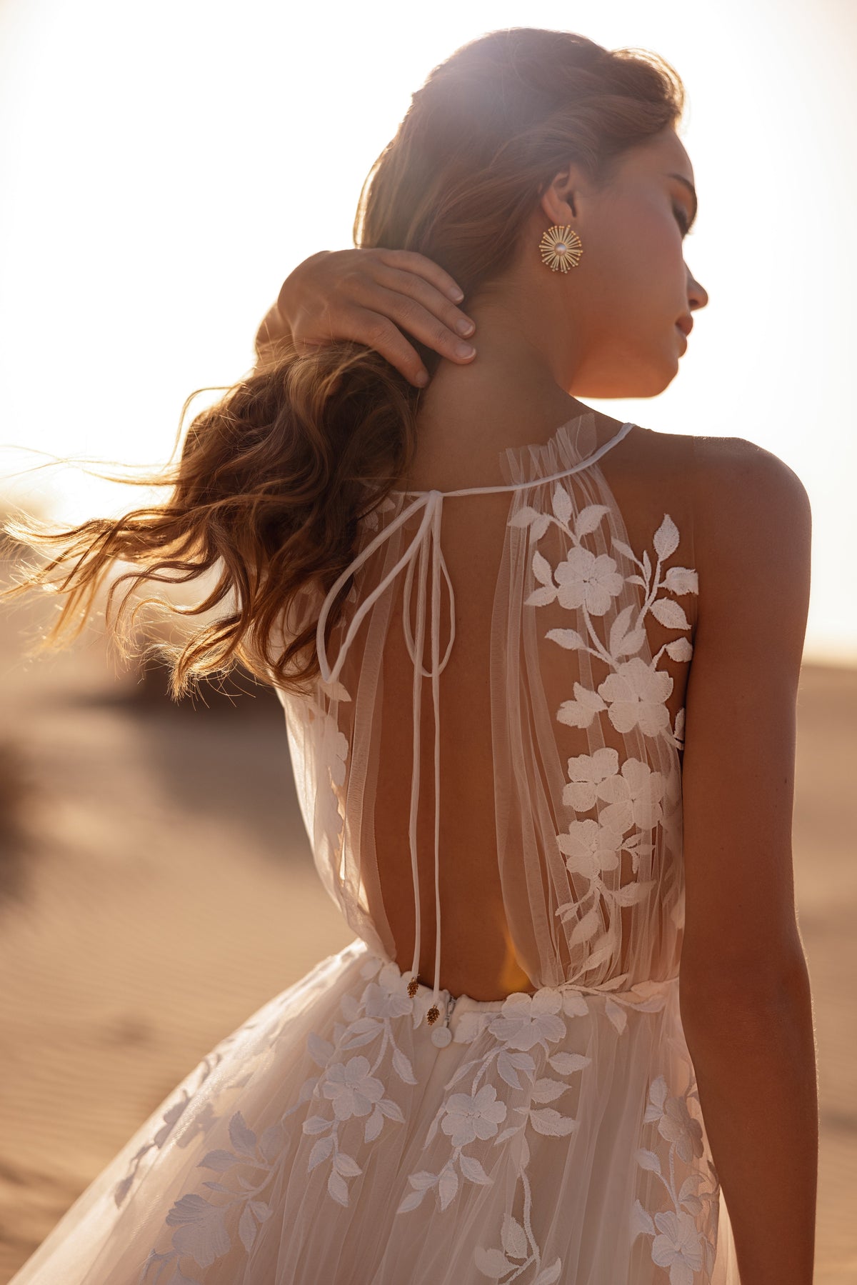 L’abito da sposa Ellie risplende nella luce del deserto, con corpetto in pizzo floreale trasparente e gonna fluida in tulle.