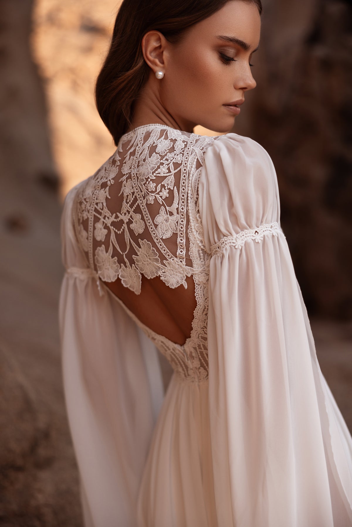 L’abito da sposa Etra presenta un raffinato retro in pizzo e uno strascico fluido, per chi cerca un’eleganza disinvolta.