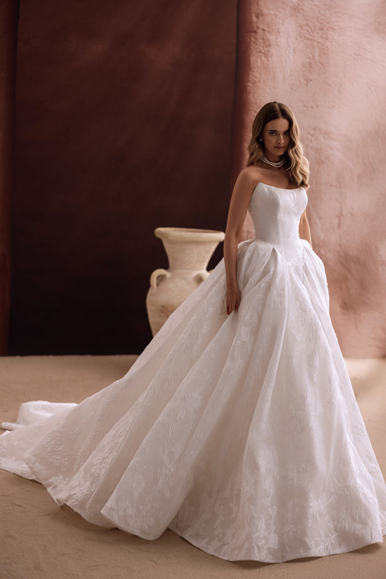 L’abito da sposa Hebe, con lungo strascico cattedrale e corpetto senza spalline, crea un look ispirato alle fiabe.