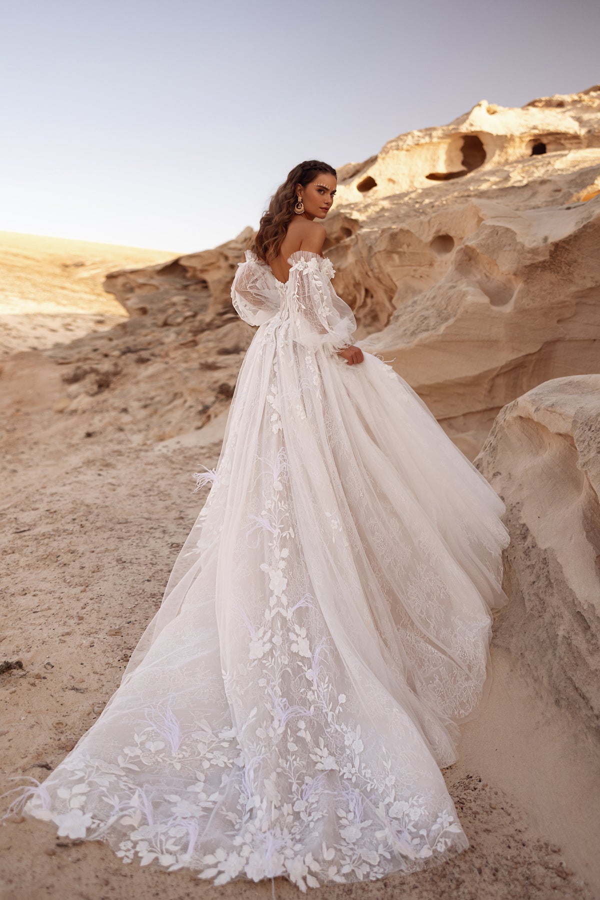 L’abito da sposa Huda, con strascico ricamato a fiori e gonna in tulle a strati, esprime un glamour da fiaba.