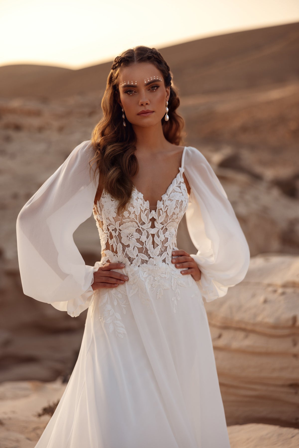 L’abito da sposa Judith presenta un corpetto in pizzo e maniche leggere in chiffon, per una sposa boho romantica.